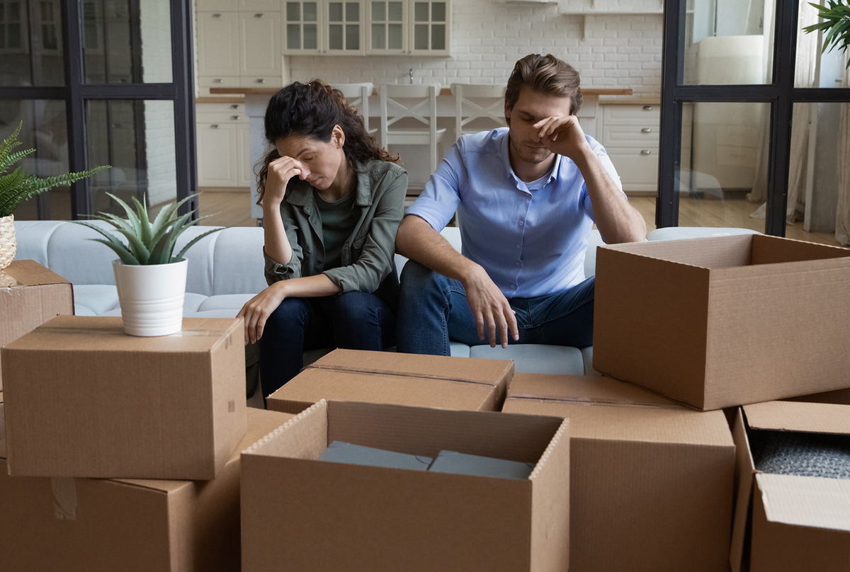 A couple surrounded by moving boxes. 