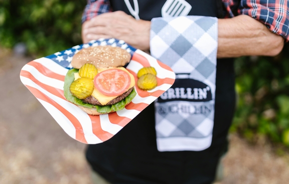Person holding a plate with a open faced hamburger on it
