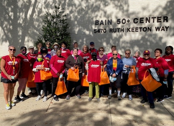 Group photo of older adults outside Bain 50+ Center wearing red AARP shirts