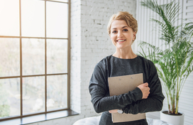 White female dressed professionally, holding a folder