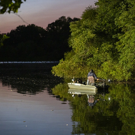 man fishing in a boat at night