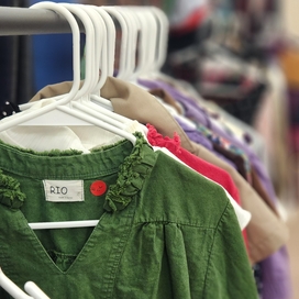 Clothes hanging on rack with hangers. First item is olive green shirt.