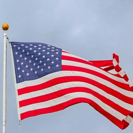 American flag on flag pole outside with sky in the background